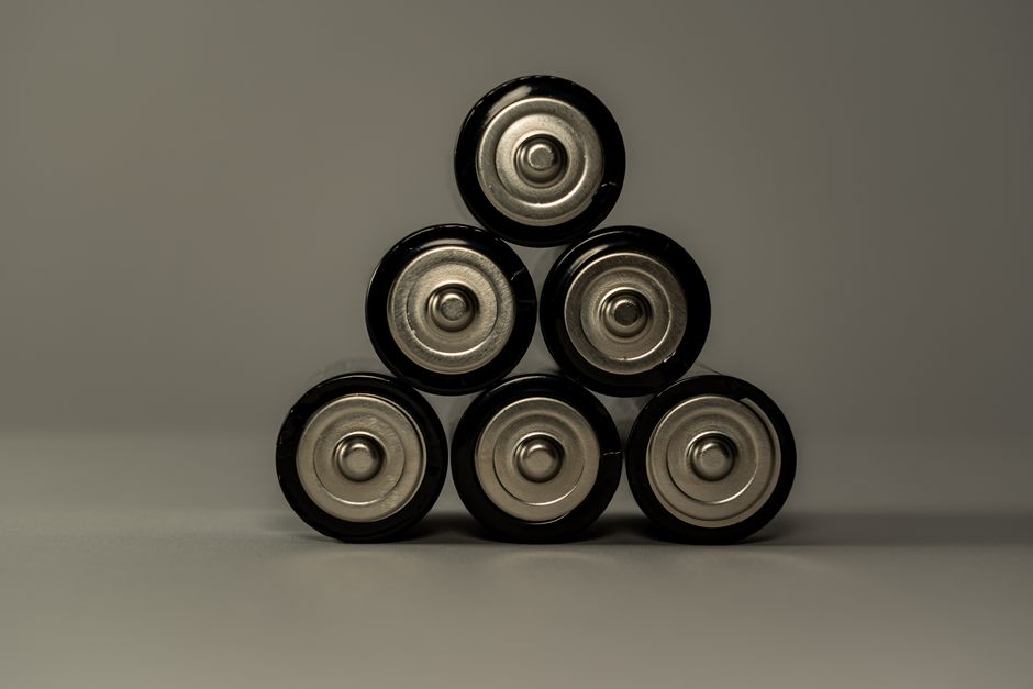 Een technicus sluit een thuisbatterij aan, met zonnepanelen op de achtergrond, voor duurzame energieoplossingen.